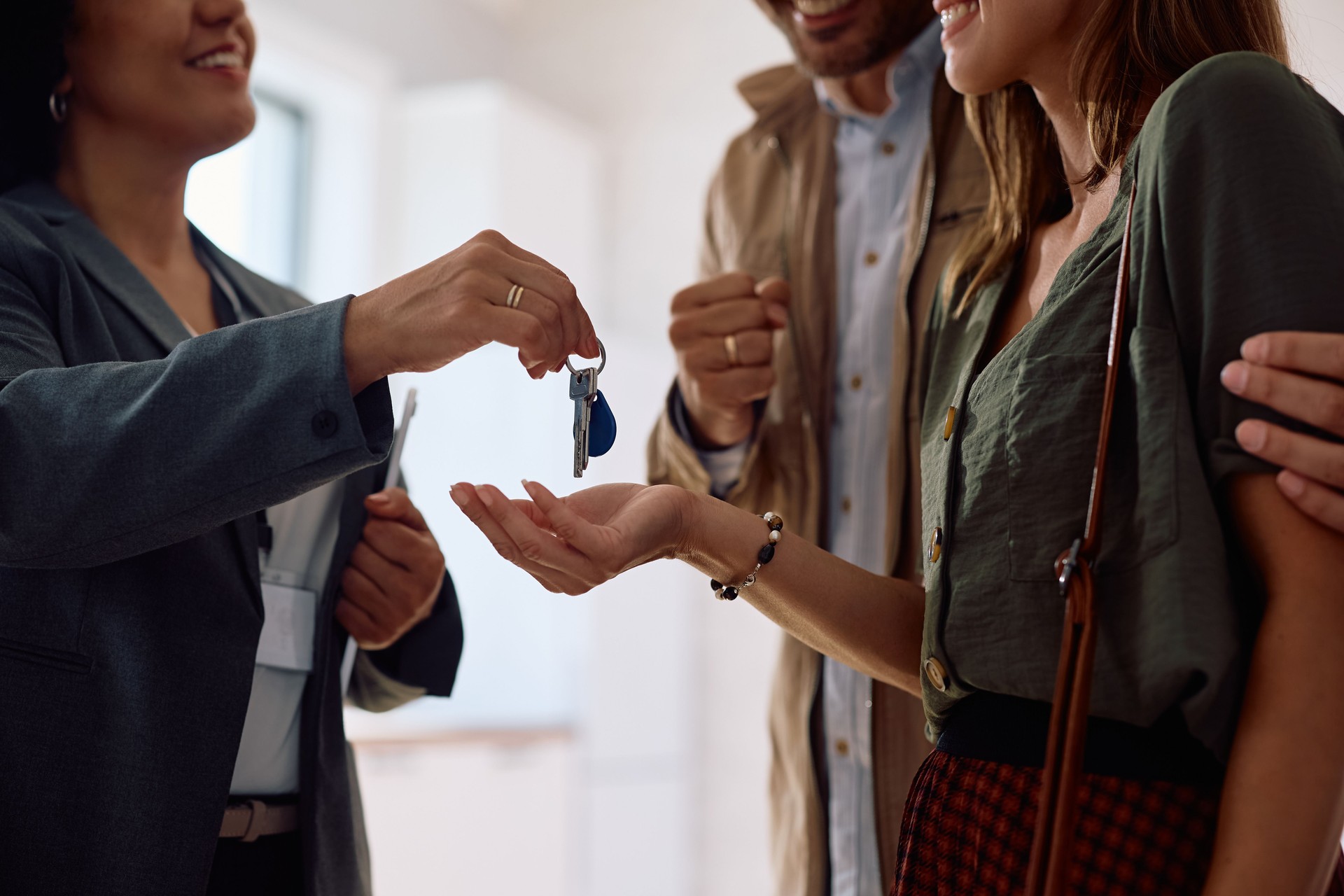 Close up of real estate agent giving new house keys to a couple of buyers.
